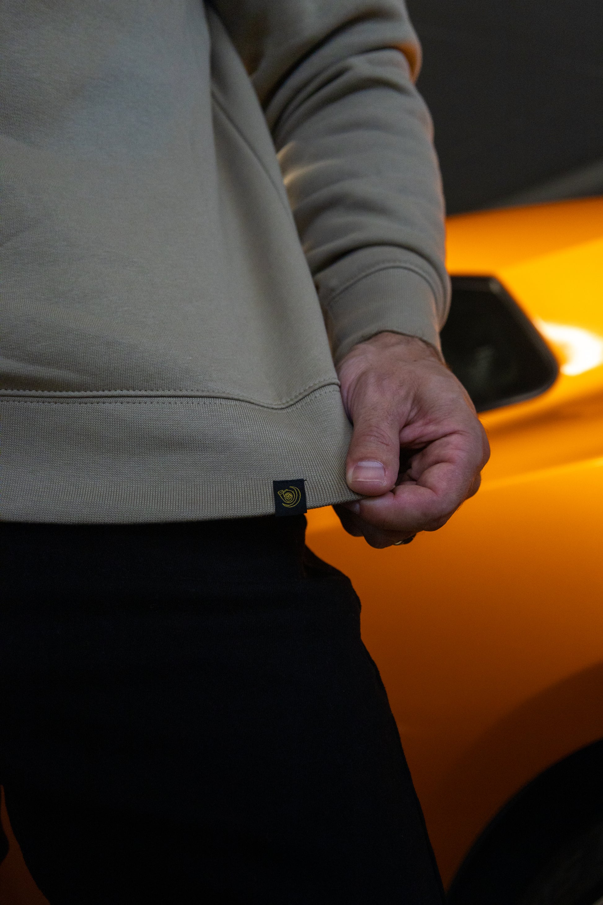 Close-up of Lucid Auto Company's signature woven hem tag on the embroidered Bin Chicken Turbo Jumper - car culture streetwear designed in Australia